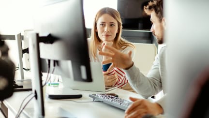 Two collegues looking at a monitor in an office